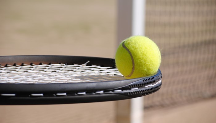 Tennis ball balanced on tennis racquet