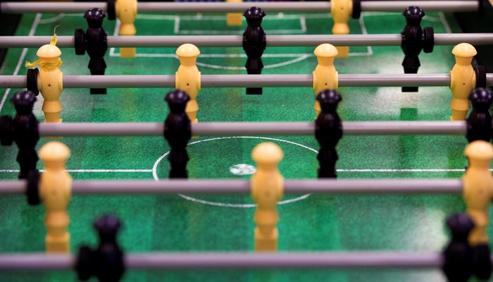 Close up image of table top football, with yellow and black wooden figures against a green background.
