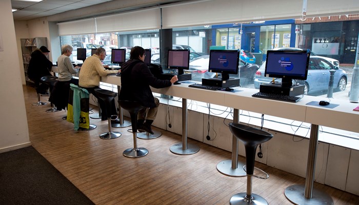 PC's at Anniesland Library. These particular PC's are located at the large windows in the library. There are four adults perched on high chairs at the PC's