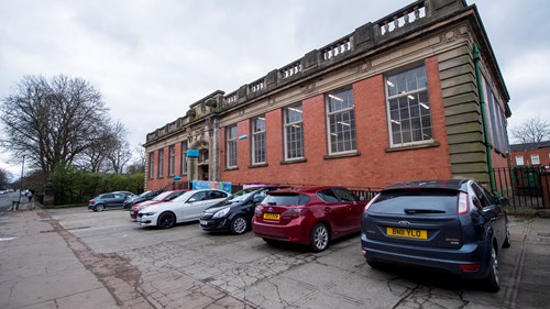 External photograph of the Shettleston Library building, with multiple cars parked outside.