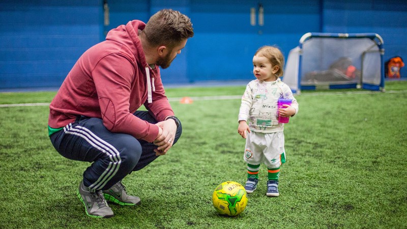 A football coach speaking to a young child during a session