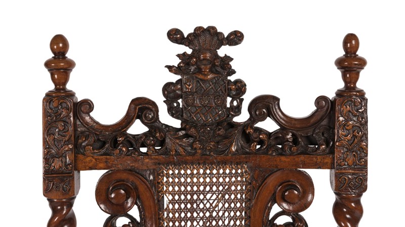 detail shot of the top of an ornately carved chair showing a coat of arms