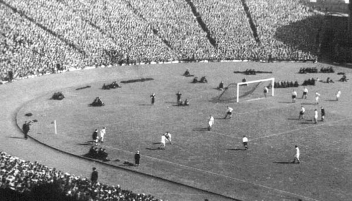 A black and white photo of a large crowd watching a football match.