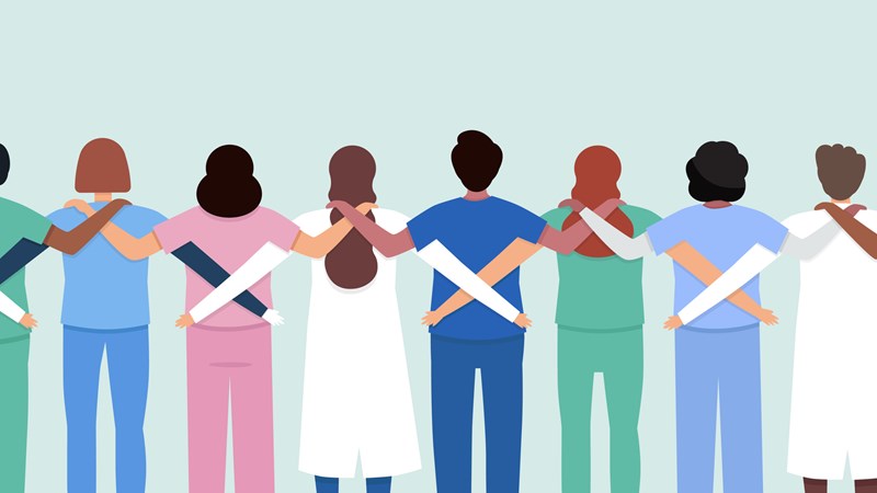 A row of people with their backs to the viewer - all supporting each other with their arms around each other. They are wearing medical outfits.