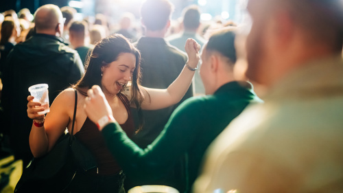 Audience members dancing and enjoying a live music performance in a vibrant festival atmosphere.