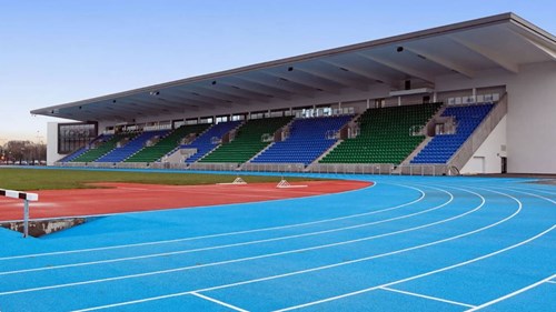 blue running track with sheltered spectator area towards the right of the track
