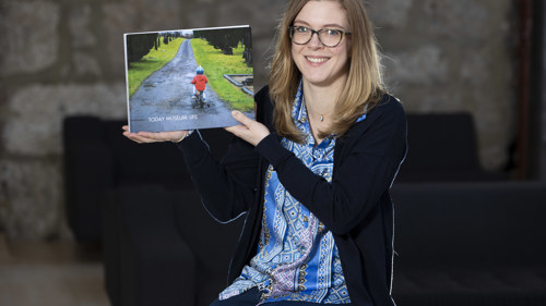 Artist Rebecca Fraser poses with a publication from a community project
