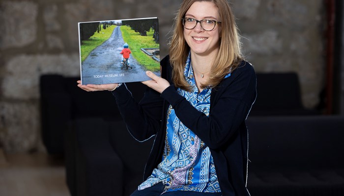 Artist Rebecca Fraser poses with a publication from a community project