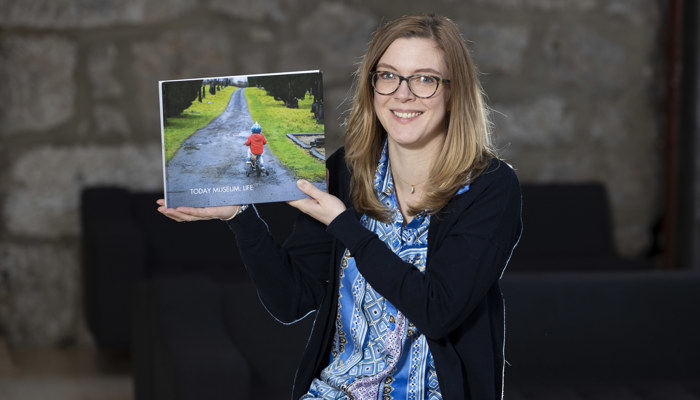 Artist Rebecca Fraser poses with a publication from a community project