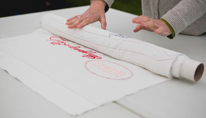 A large fabric art work shows stitched writing reading "An Idea Shopping List"