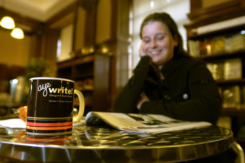Woman reading Aye Write brochure in library