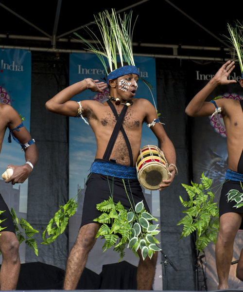 Men in traditional dress performing a dance on stage at Glasgow Mela