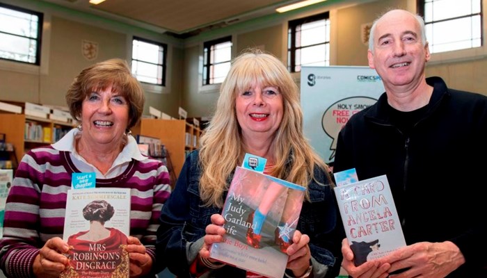 Three members of the book club holding up books