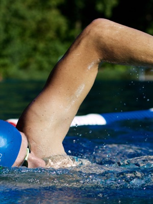 A man wearing a blue swimming cap is practicing front crawl in the swimming pool