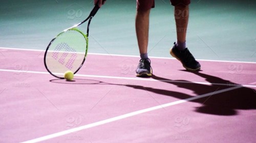 close up of someone with tennis racket and ball on court 