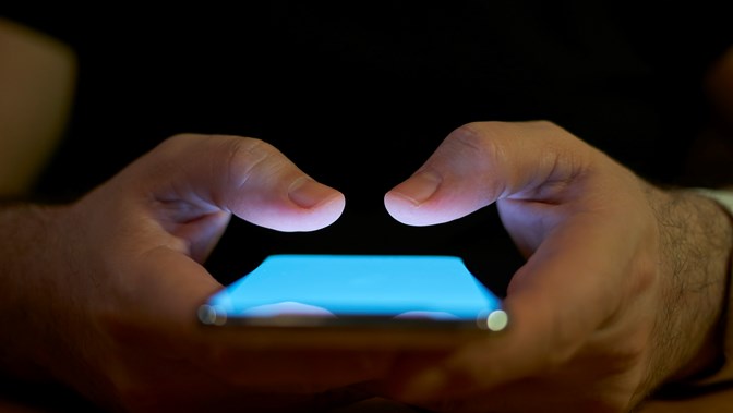 Close up of a person's fingers tapping a phone with a blue screen