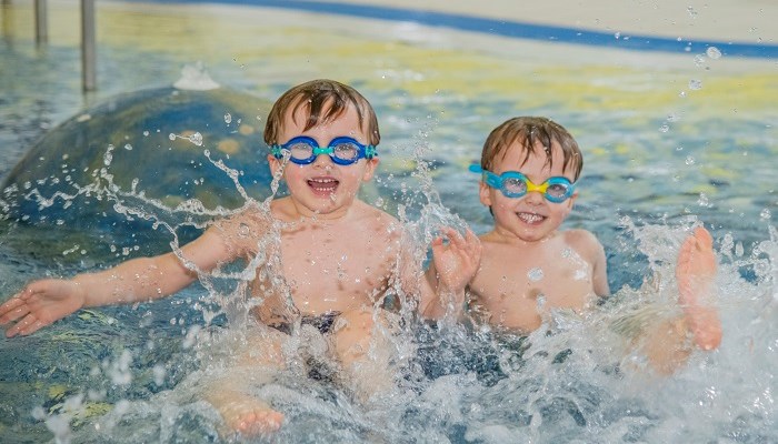 Two children smiling while playing in a swimming pool together