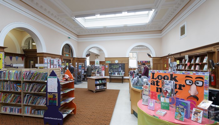 An interiror shot of Pollokshields library with a book display in the foreground.