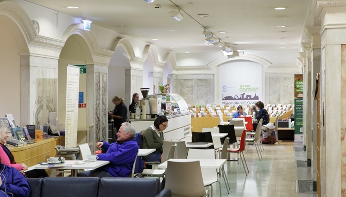 Interior shot of seating area at Library at GoMA, featuring people reading and chatting over coffee.