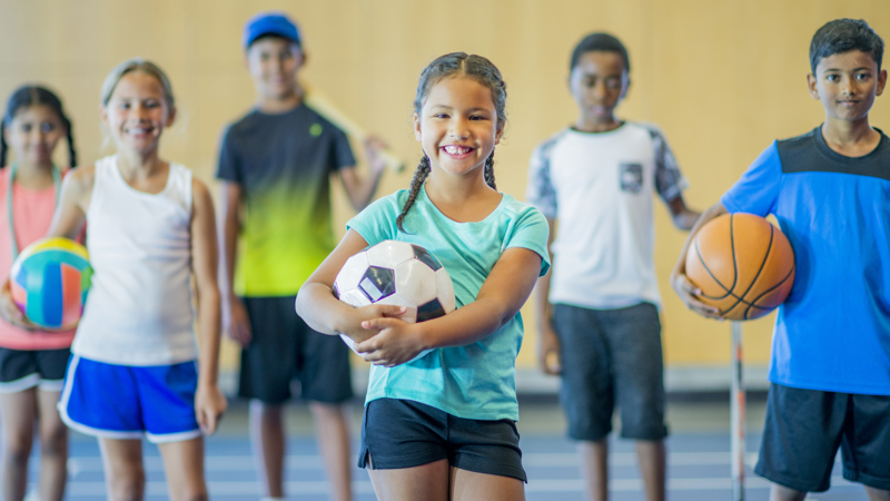 a group of boys and girls holding different sporting equipment