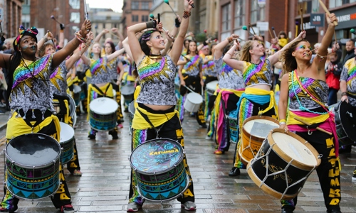 Women in vibrant costumes playing the drums.