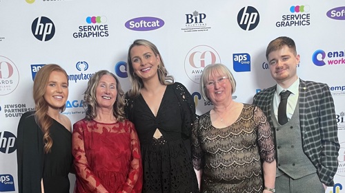 A group of five people standing together and smiling for a group photo at an awards event