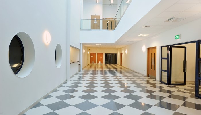 large open space on the bottom floor of a building. The walls are painted white and the flooring has a black and white checked effect