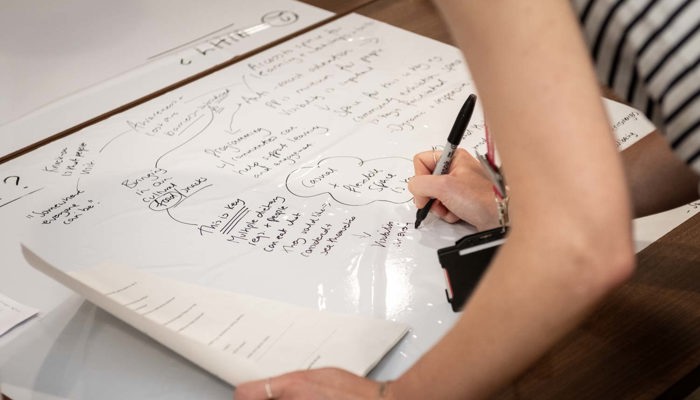 Close-up of a person writing ideas and notes on a large sheet of paper during a workshop.