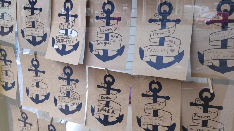 A set of postcards decorated with anchor symbols hangs in a shop window