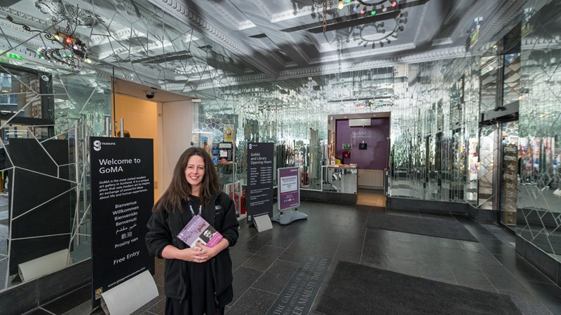 Photograph shows a gallery assistant welcoming visitors to GoMA in the entrance lobby.