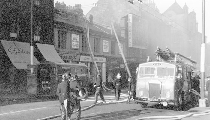 A black and white photo of a theatre in Glasgow with an old fashioned fire engine and fire fighters tackling a blaze that ultimately destroyed it.