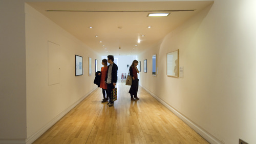 Visitors look at pictures on a gallery wall at GoMA