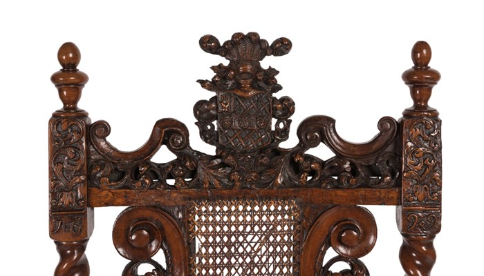 detail shot of the top of an ornately carved chair showing a coat of arms