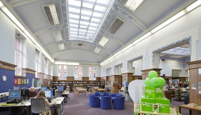 The PC area of the library which also has a table and soft blue chairs for reading or for meeting groups. The high ceiling is curves and has a long, grid, colonial-style skylight.