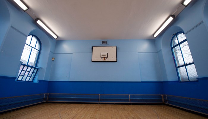 sports hall with wooden floors and blue walls. there are windows on the left and right of the room