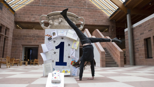 Mia cartwheels in front of giant first anniversary card at Burrell Collection