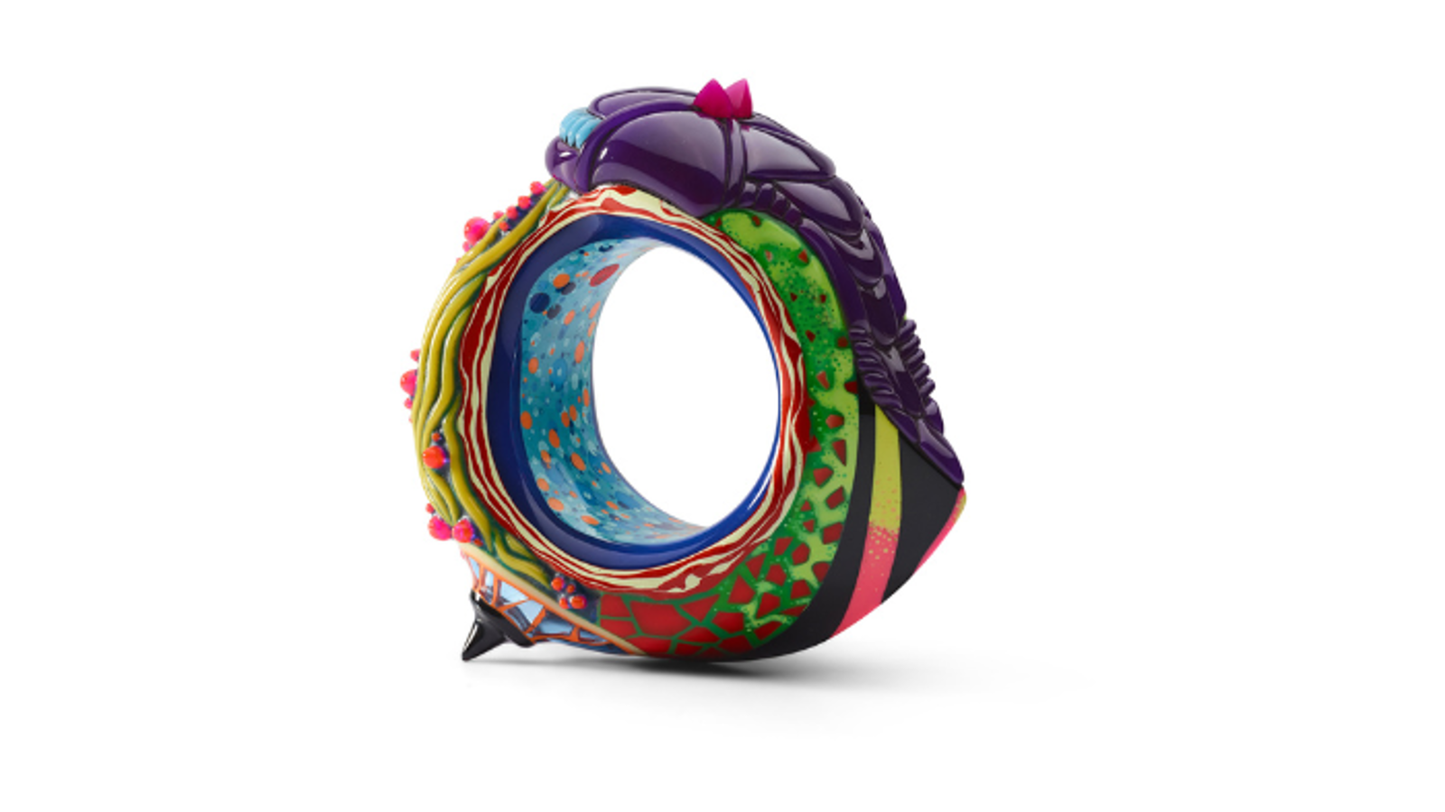 A colorful, sculptural ring-like object with intricate multicolored patterns, raised bead-like details, and a purple segmented top, photographed against a white background.