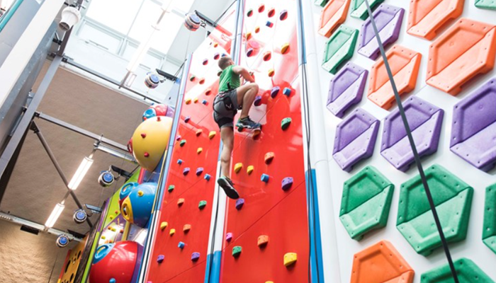 child climbing up a colourful climbing wall