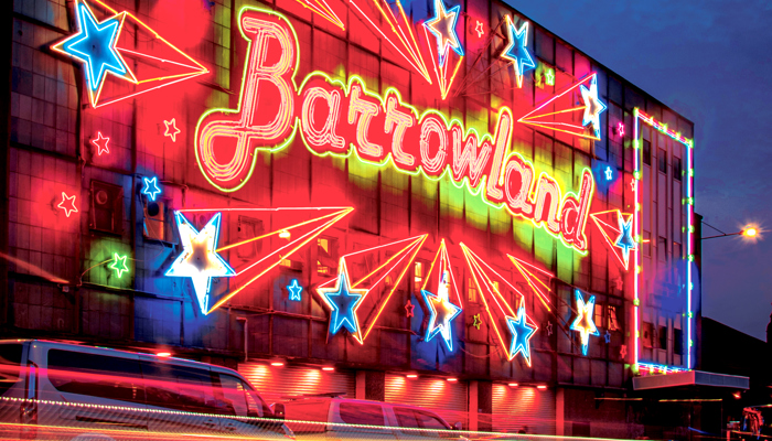 External shot of the Barrowland venue at night. The name of the venue is lit up in red and yellow, with illuminated stars all around.