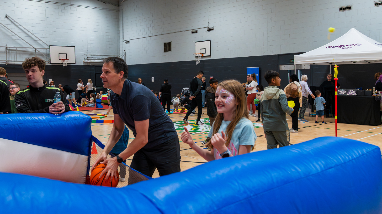 A father and daughter playing inflatable basket ball at Glasgow Club Springburn during Summer of Fun 2025.