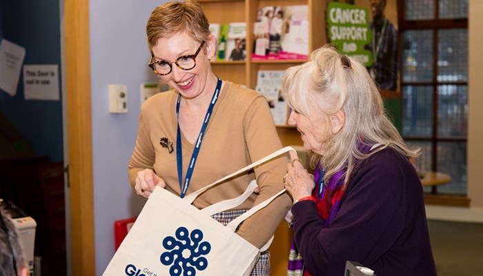 Two volunteers in a library putting books in a canvas bag