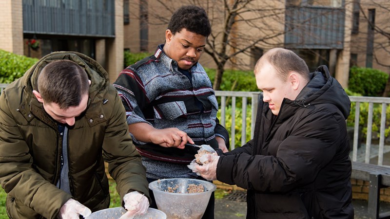 Three people in an outdoor setting mixing food in bowls