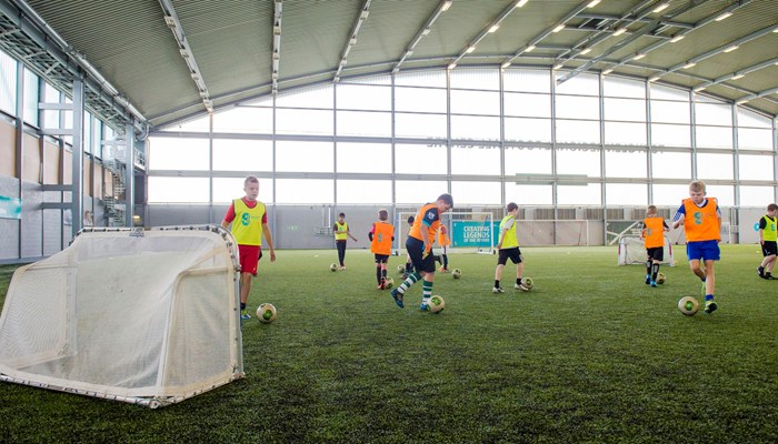 A group of children dribbling footballs while playing indoors at Toryglen