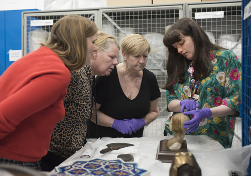 Project Curator Laura Bauld looking at an object with members of a local community group