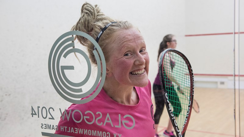 Two people playing squash at Scotstoun with one smiling at the camera