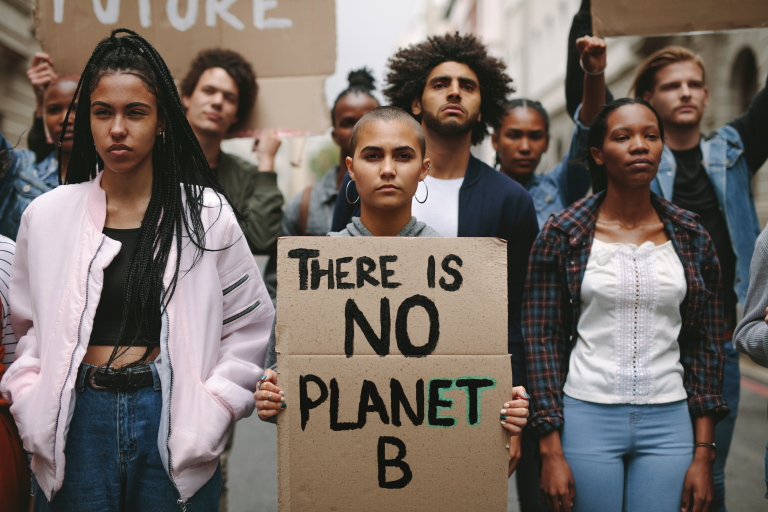 photograph showing people at a mock protest rally. one person holds a sign reading "there is no planet B"