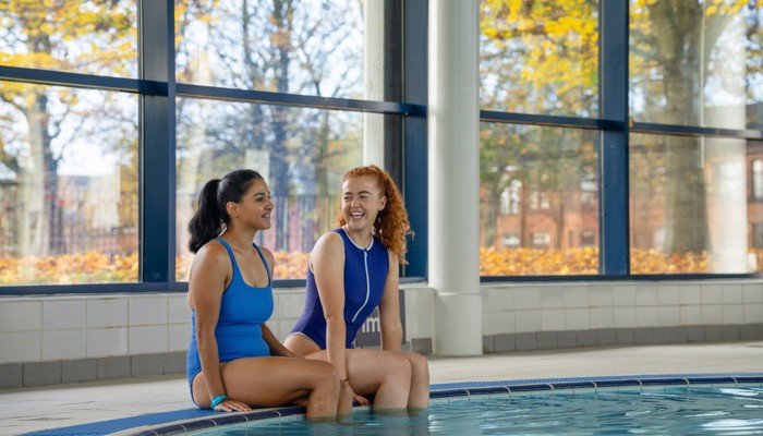 Two Glasgow Club members sit by a swimming pool