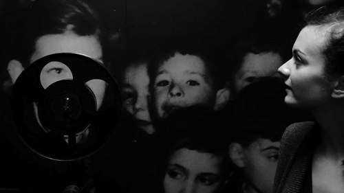 A still from a black and white film showing children and a projector