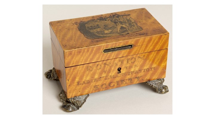 an ornately accented orange-yellow wooden box with short metal legs.