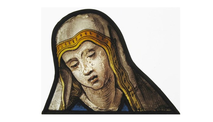 fragment of stained glass showing a shrouded figure in a gold and white shroud